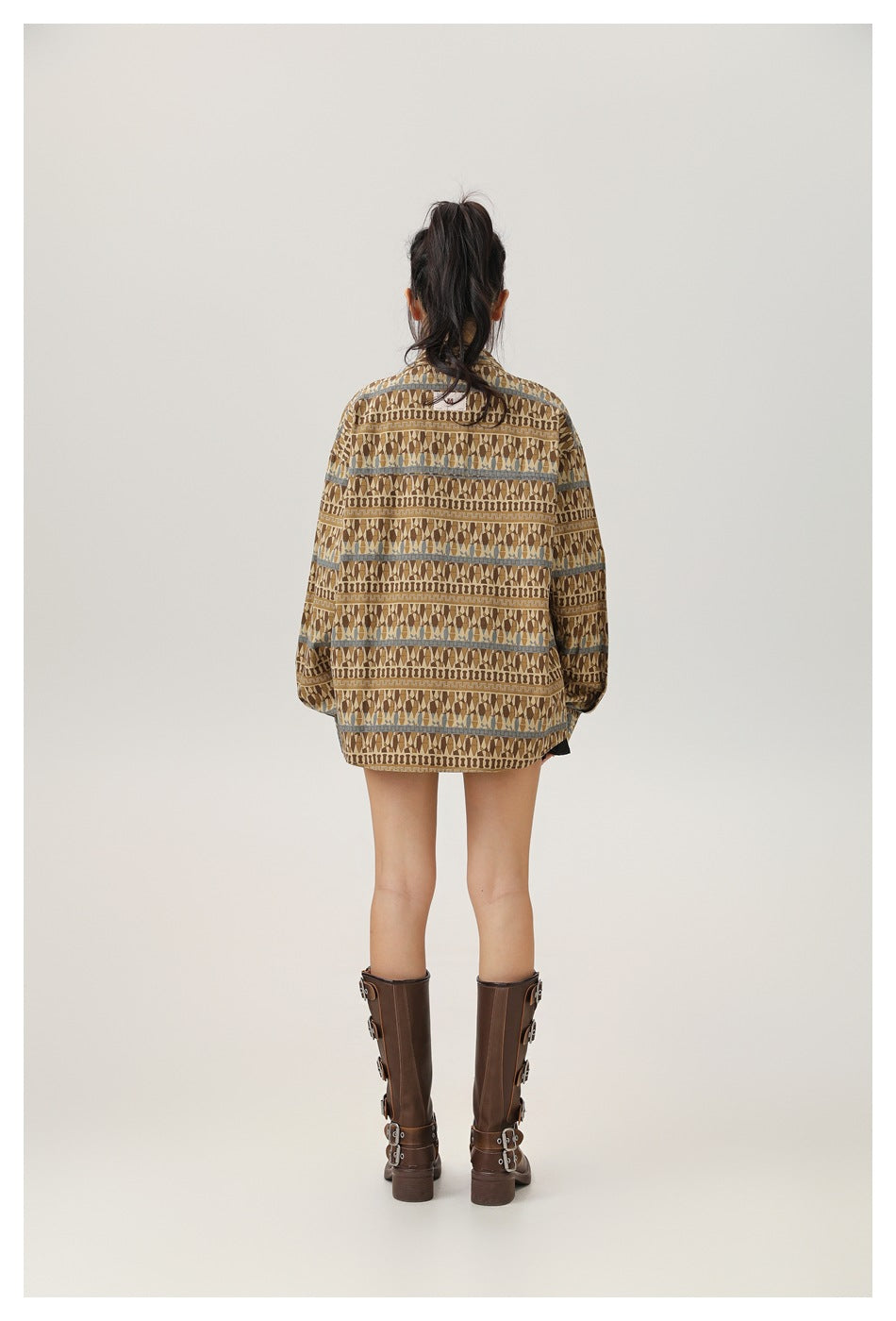 Back view of a model wearing an oversized brown geometric-patterned button-up shirt with long sleeves.