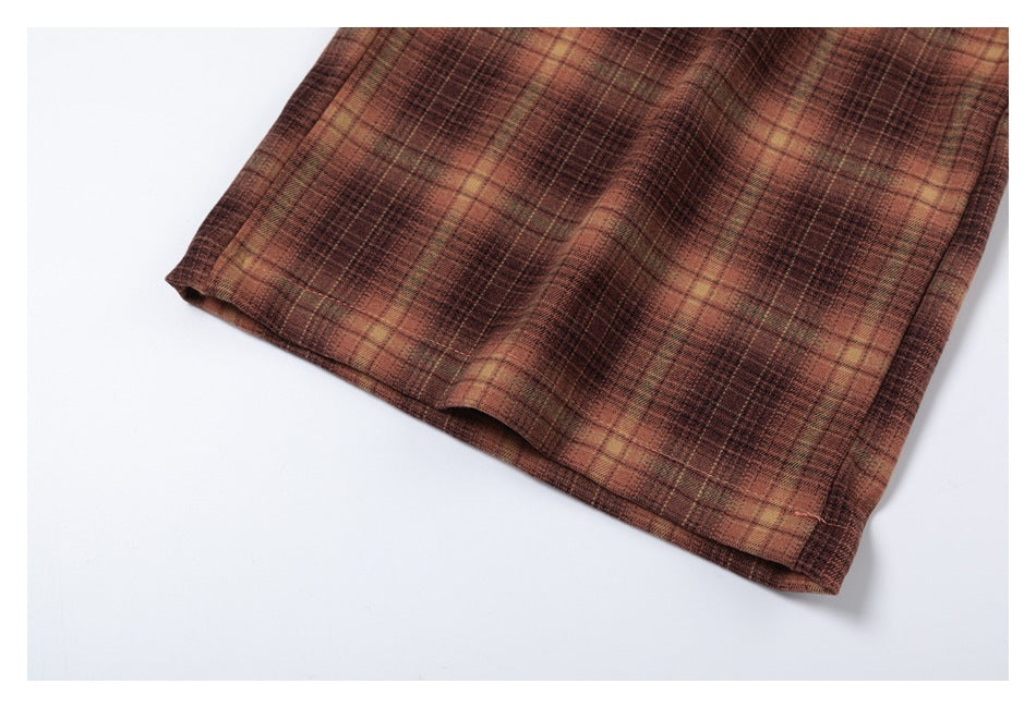 Close-up of the stitched hem on brown and tan plaid trousers.