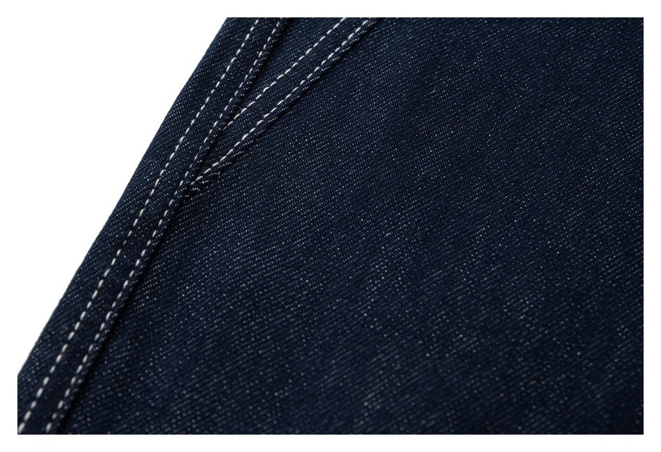 Close-up of dark indigo denim with a curved edge and rows of light contrast stitching.