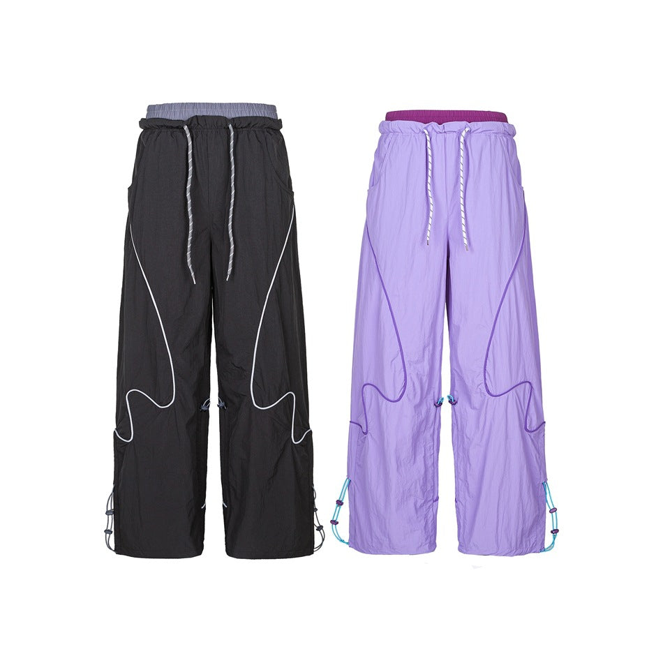 Front view of wide-leg pants in black and lavender, with drawstring waists, contrast piping, and adjustable hems.
