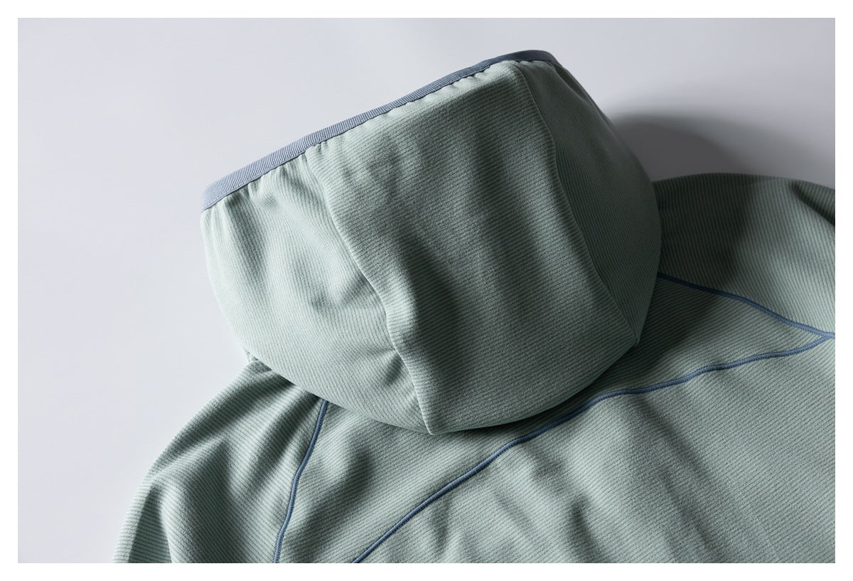Close-up of the sage-green pullover's hood and back, with dark gray-blue piping along the seams.