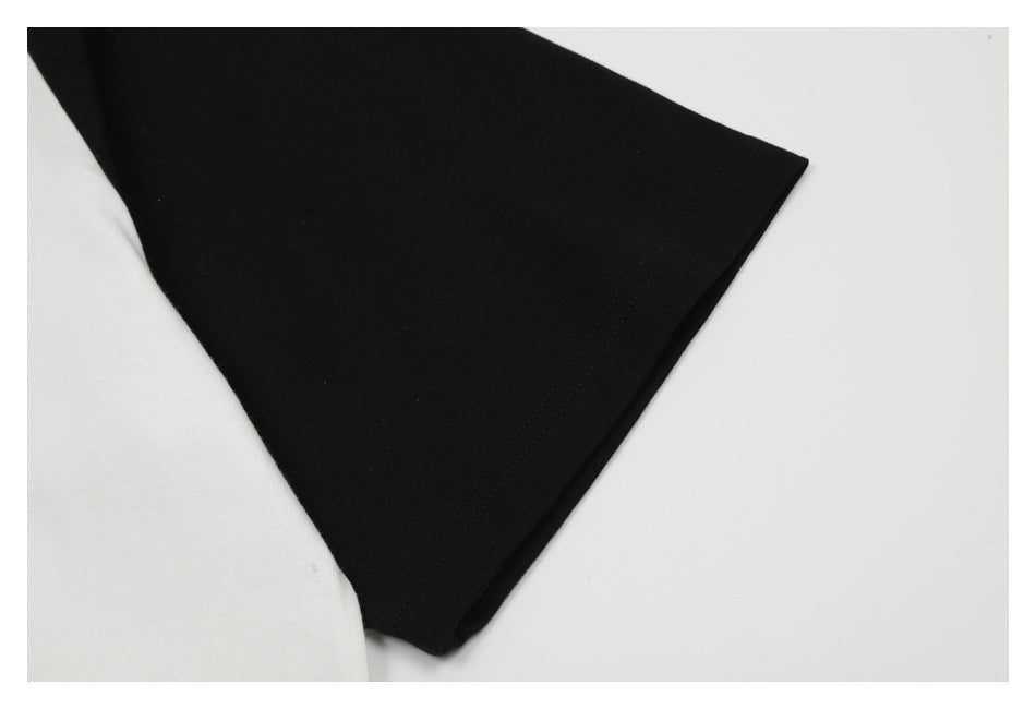 Close-up of a black short sleeve and stitched edge beside the white body of a raglan T-shirt.
