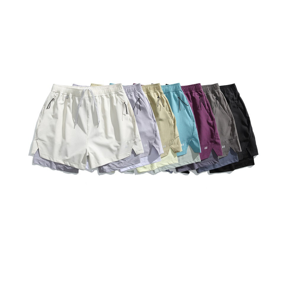 Several pairs of running shorts arranged together in white, lavender, pale yellow, turquoise, plum, gray, and black.
