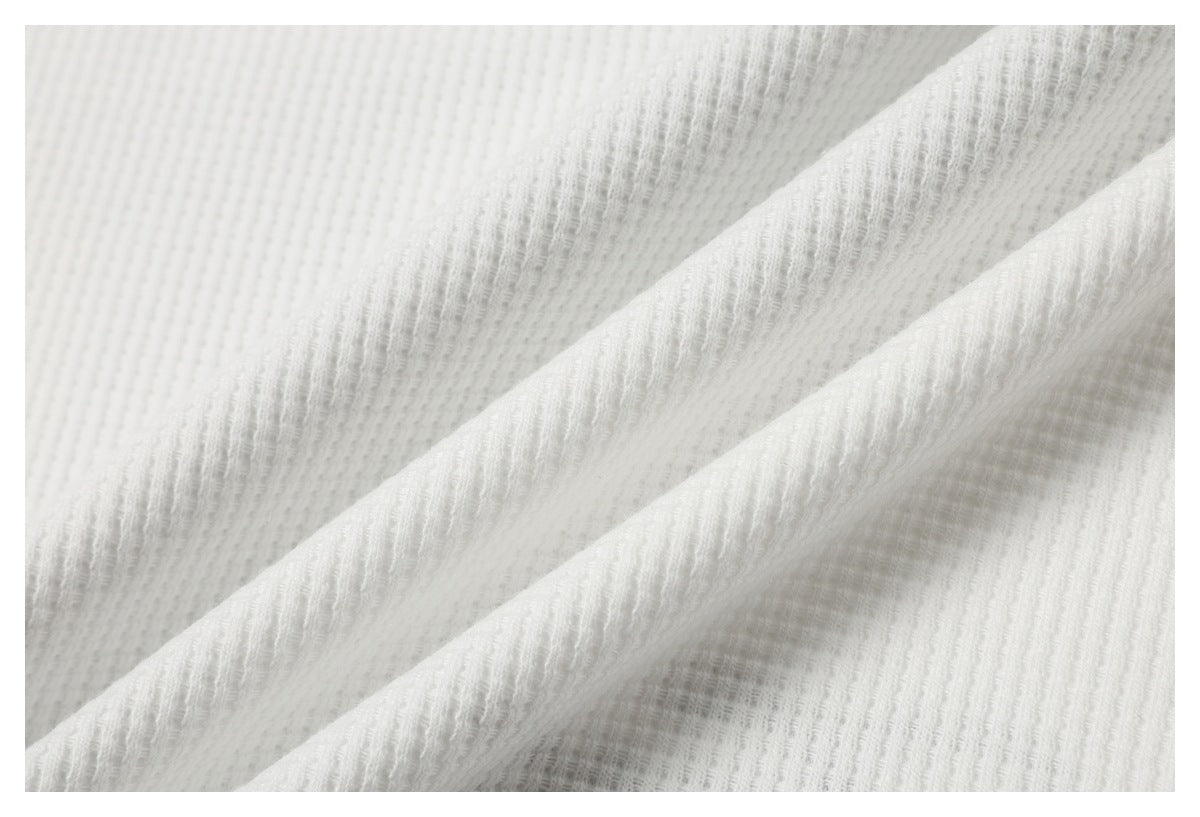 Macro view of softly folded white fabric showing its raised ribbed texture.