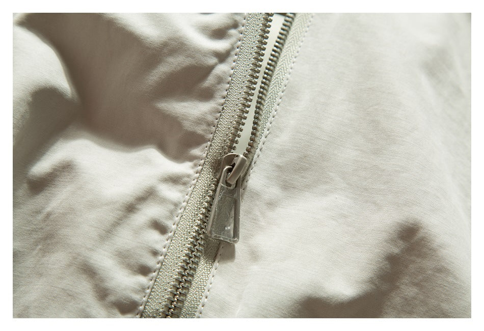 Close-up of the light beige jacket's front zipper and pull.