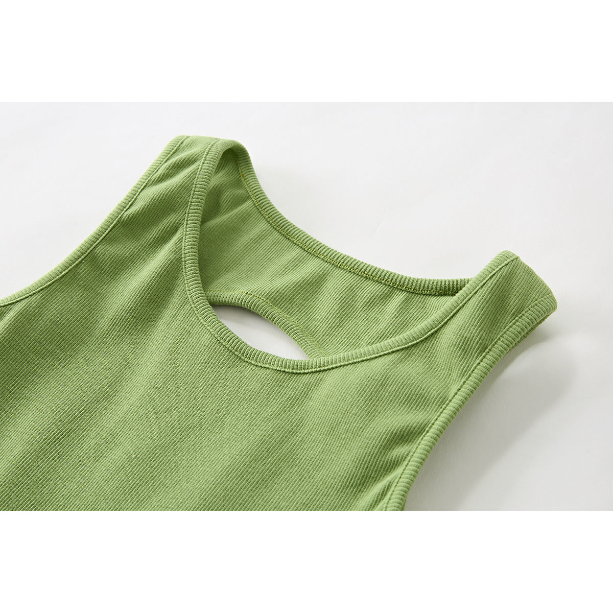 Close-up of the light green ribbed tank top’s scoop neckline and shoulder straps.