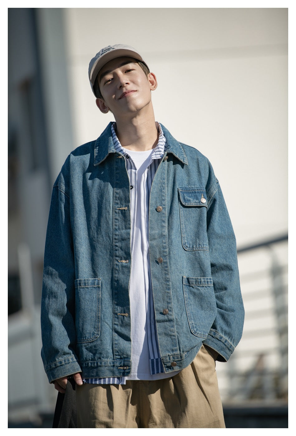 Close view of a model wearing a blue denim jacket with button closures and several patch pockets.