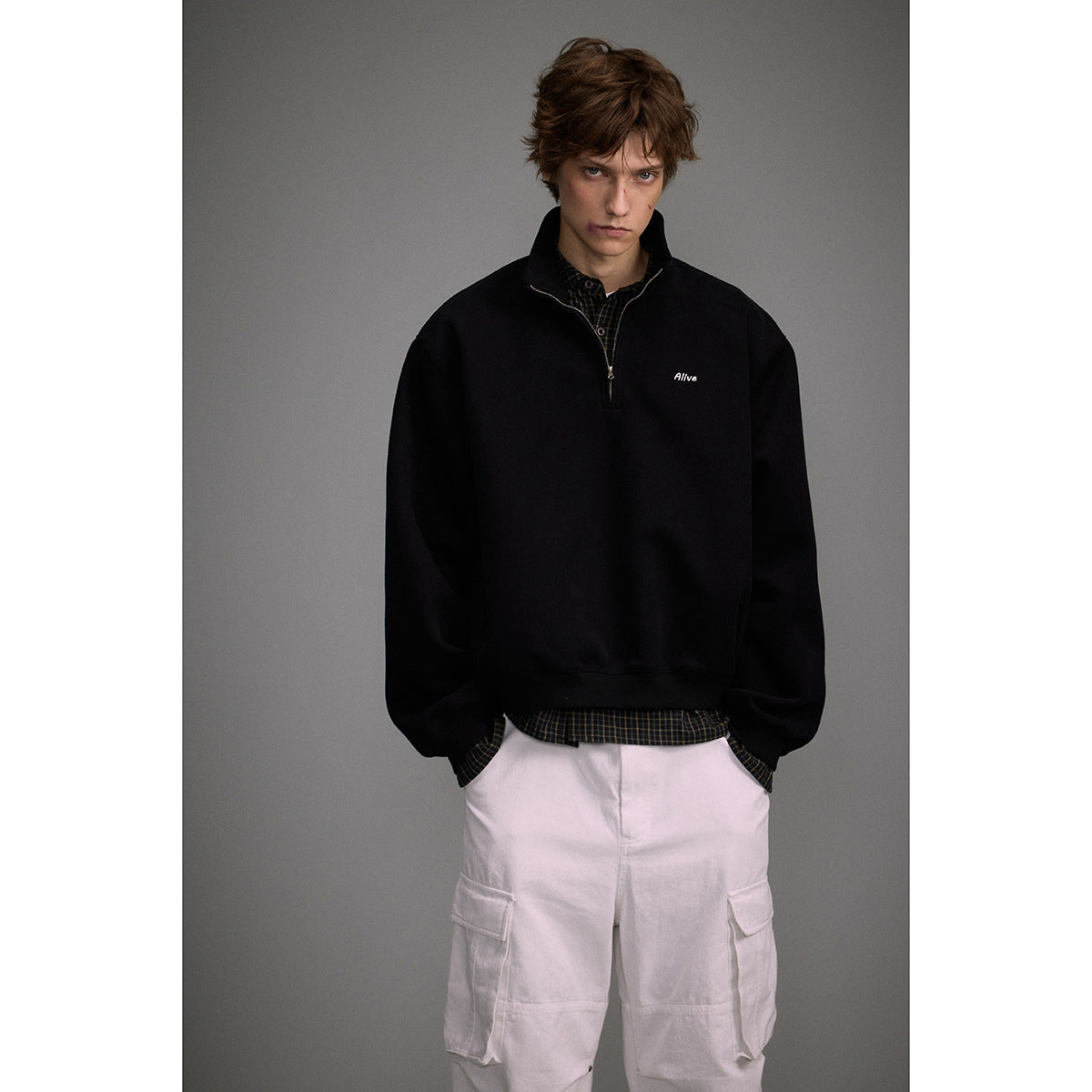 Front view of a model wearing a black quarter-zip sweatshirt with small white chest embroidery.