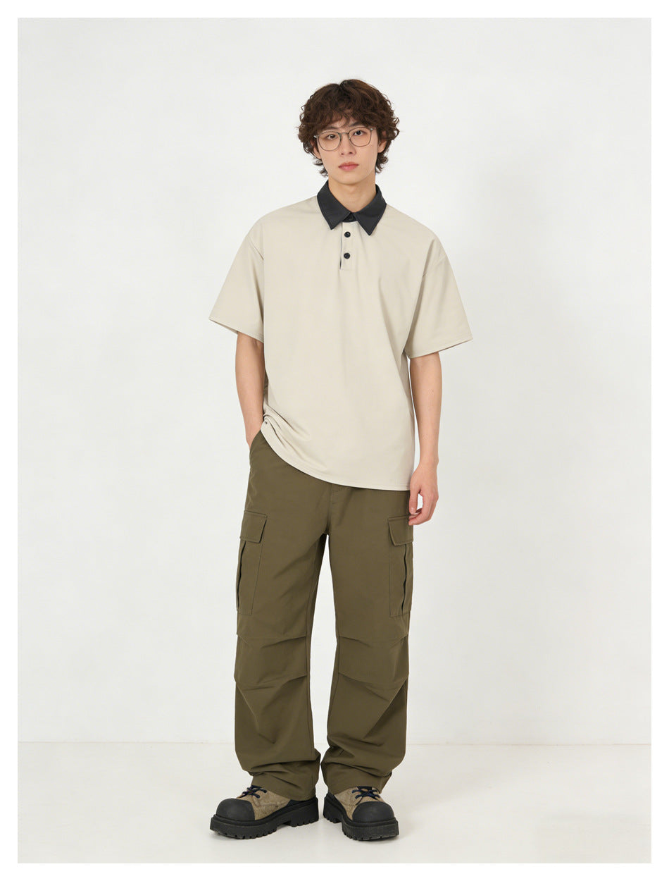 Front view of a model wearing a light beige polo with a black collar and olive cargo pants.