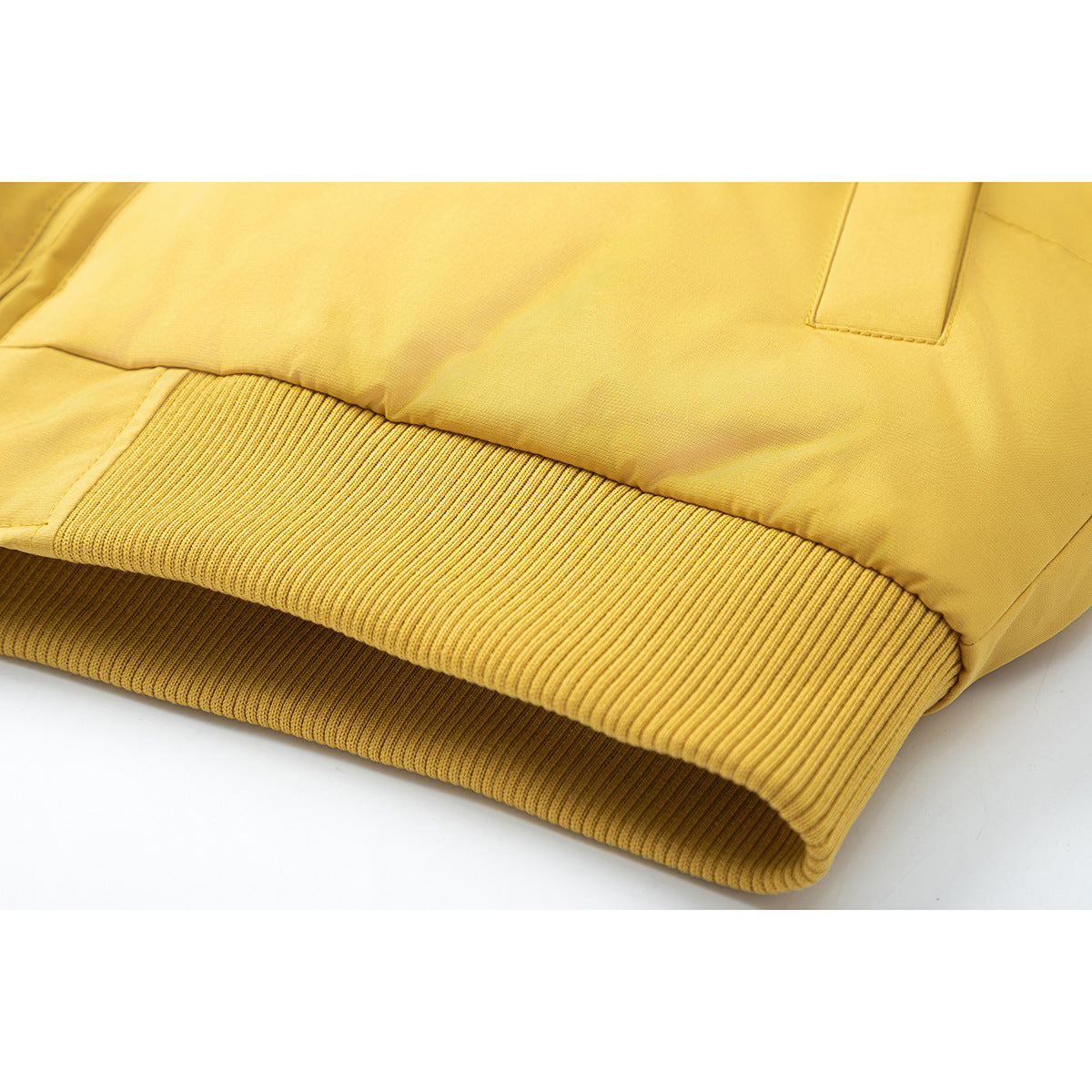 Close-up of the mustard-yellow jacket’s wide ribbed hem and lower pocket edge.