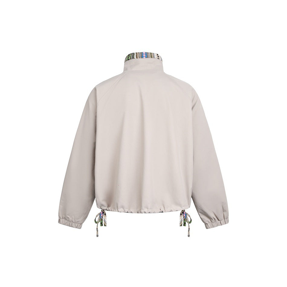 Back view of a light beige jacket with a high collar, elastic cuffs, and patterned drawcords at the hem.