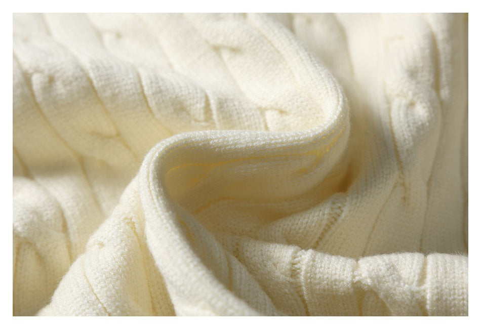 Close-up of the ivory sweater's folded ribbed neckline edge and cable-knit texture.