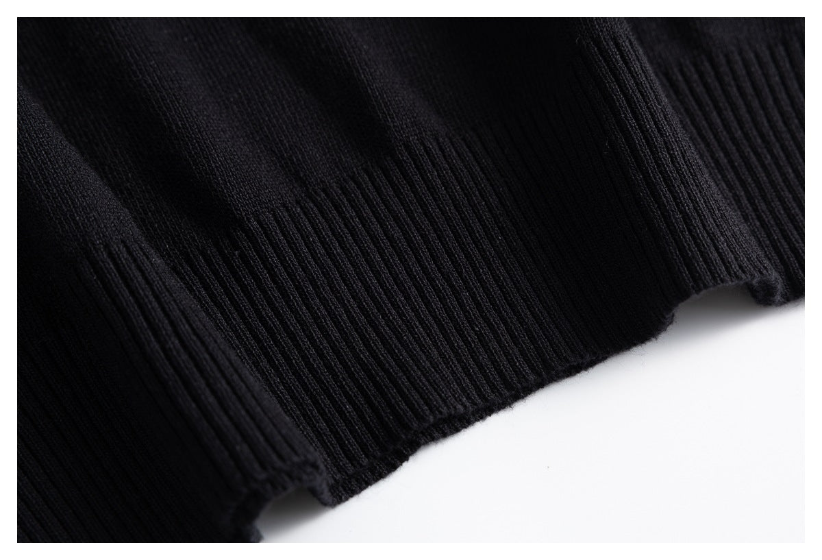 Close-up of the black rib-knit hem of a garment against a white background.