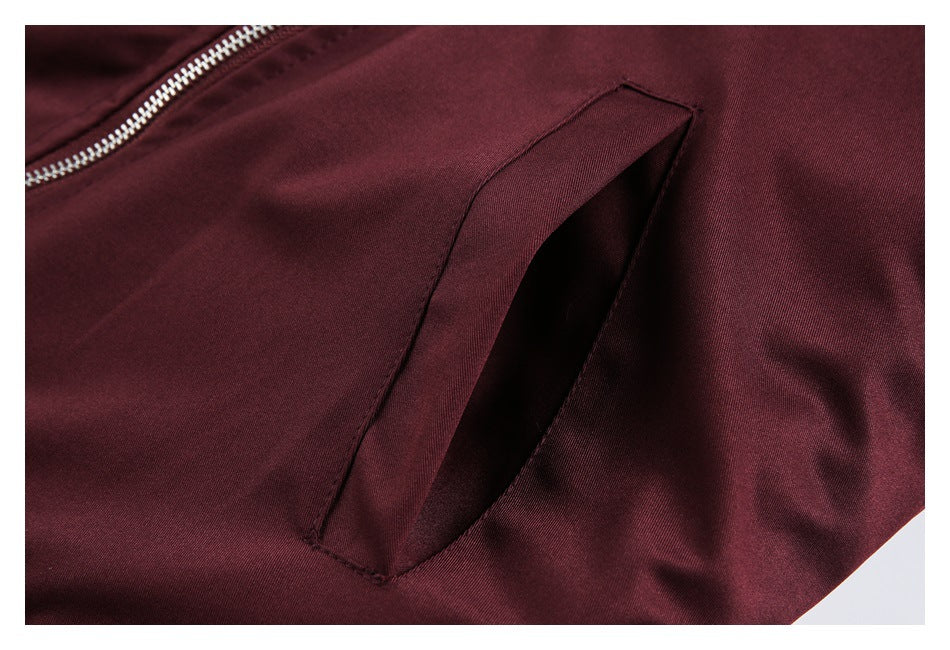 Close-up of a slanted pocket and silver zipper on a burgundy jacket.