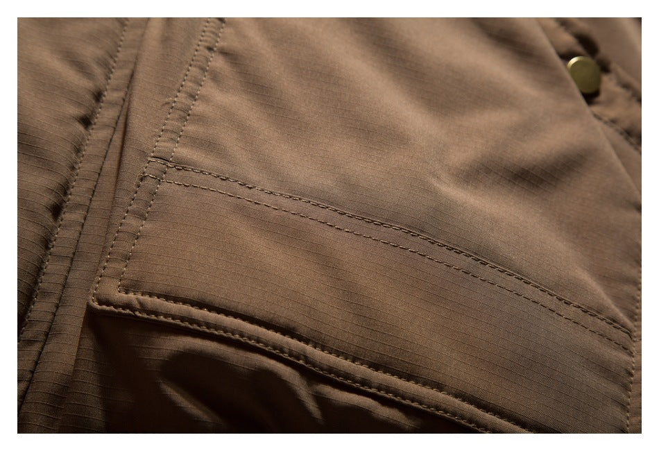 Close-up of a large stitched flap pocket on brown grid-textured fabric.