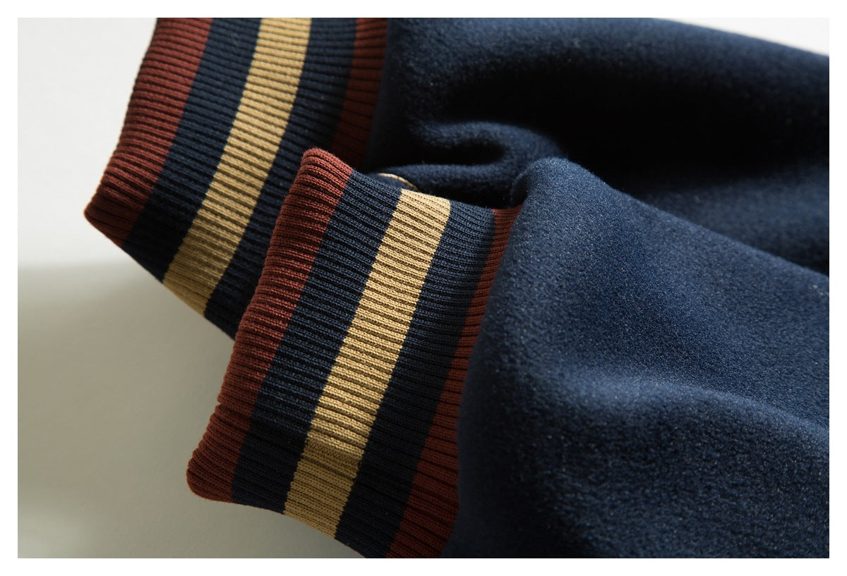 Close-up of a navy coat sleeve with a ribbed cuff striped in rust, tan, and navy.
