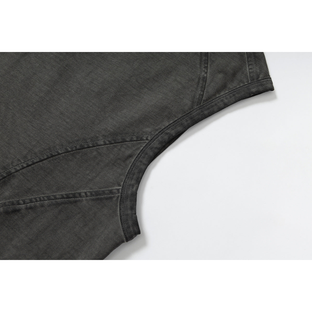 Close-up of curved panel seams and armhole binding on a washed charcoal sleeveless top.