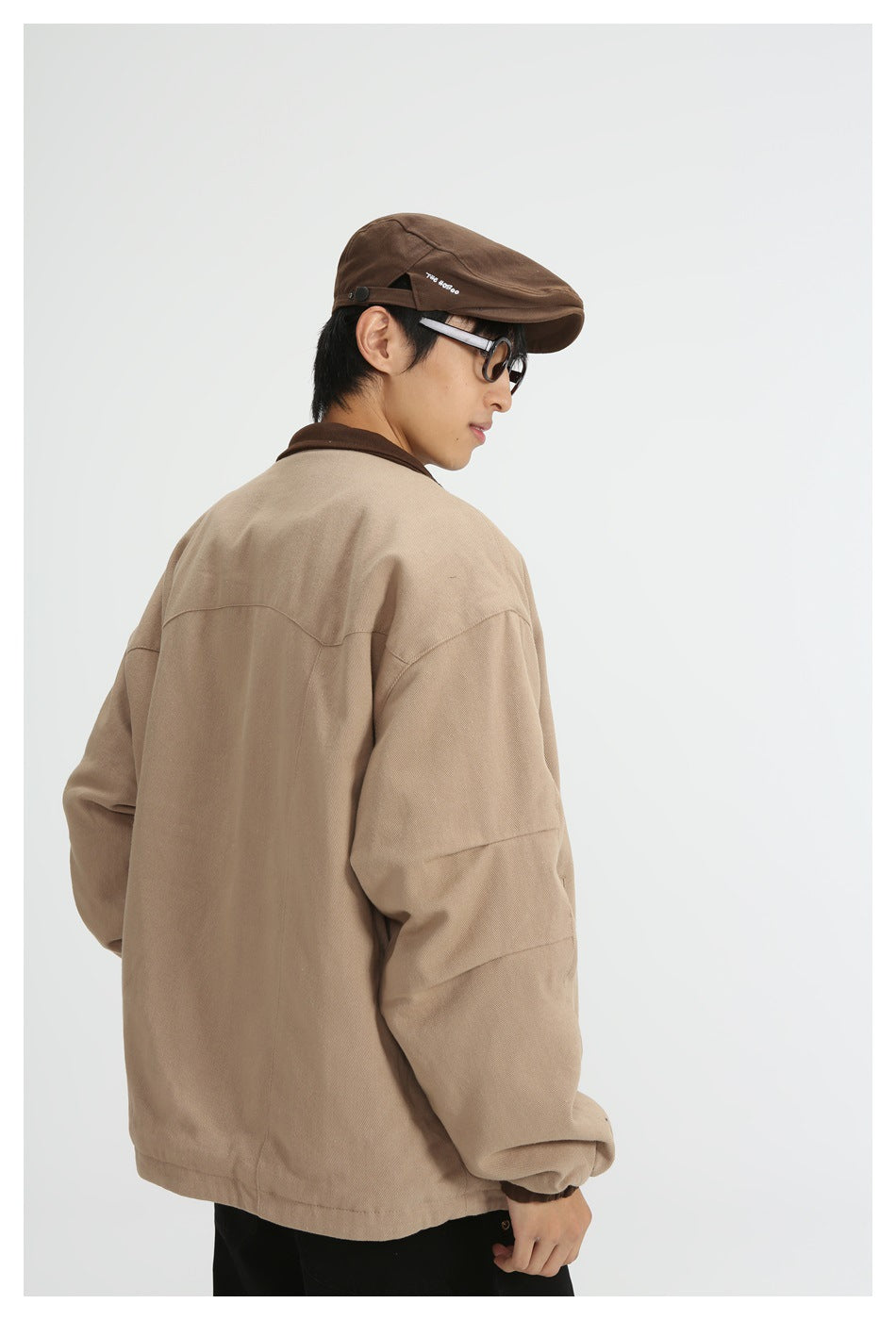 Model wearing a loose tan jacket with a dark brown collar, shown from the back and side.