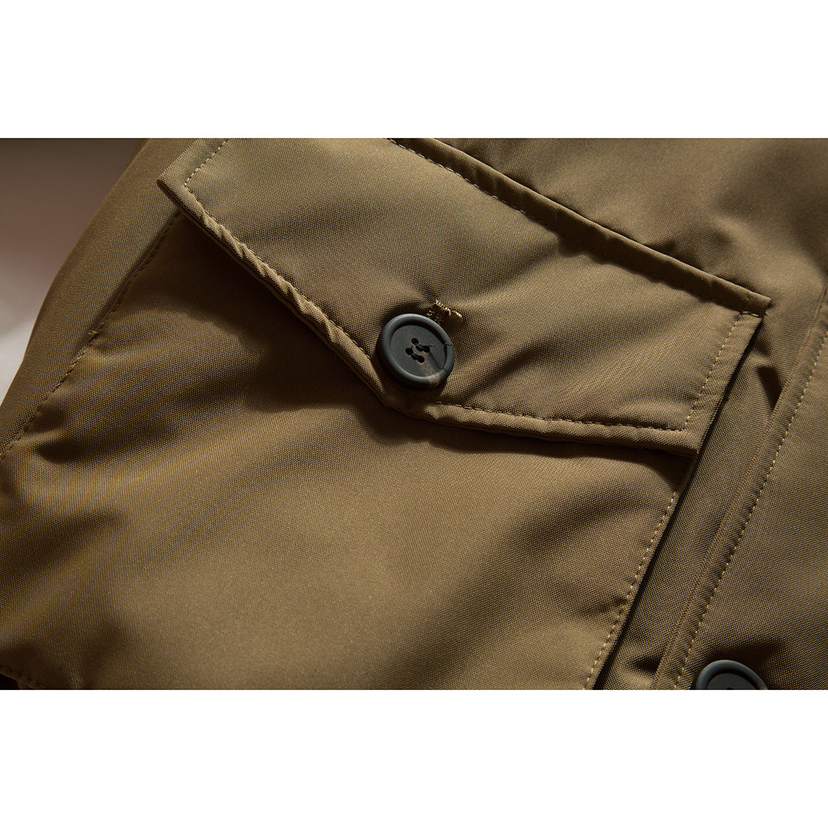 Close-up of a tan jacket's buttoned flap pocket and stitching.