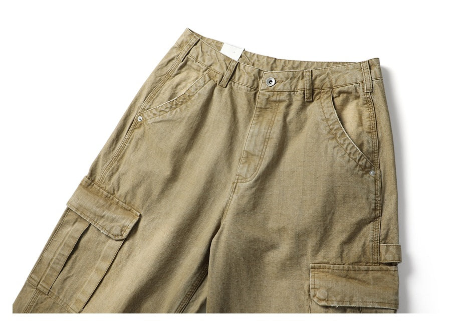 Close-up front view of khaki cargo pants with a button waist, angled pockets and flap cargo pockets.