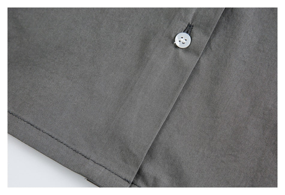 Close-up of charcoal gray fabric with a white button, buttonhole, and stitched seam.