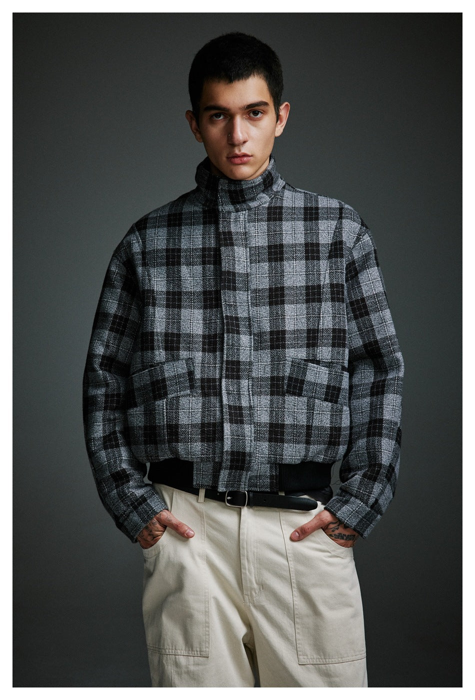 Front view of a man wearing a gray and black plaid jacket with a high collar and two front pockets.