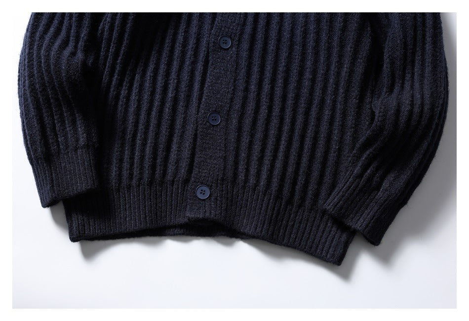 Close view of the lower front of a dark navy ribbed cardigan, showing buttons, hem and sleeve cuffs.