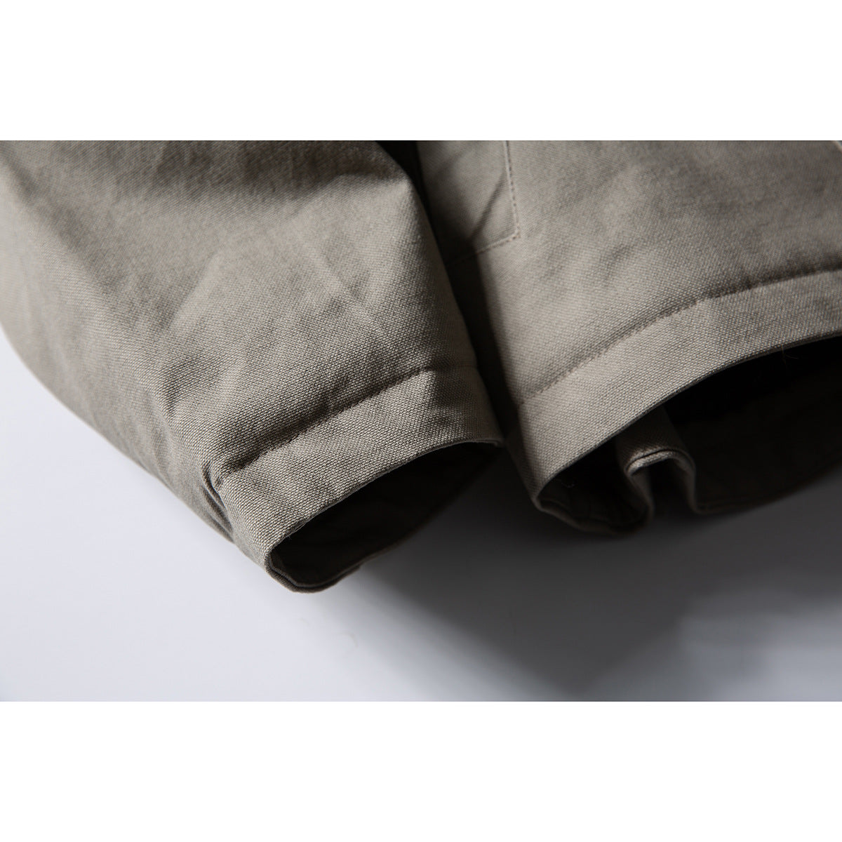 Close-up of the taupe-gray jacket's stitched sleeve cuffs and hem.