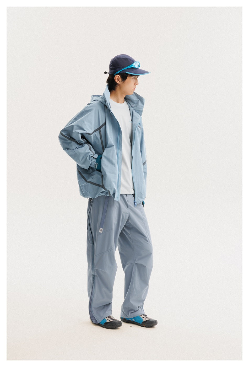 Model in a pale blue hooded jacket with dark trim and matching pants, shown in a side pose.