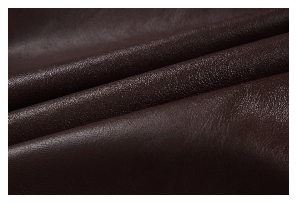Close-up of dark brown, pebbled jacket material arranged in soft folds.