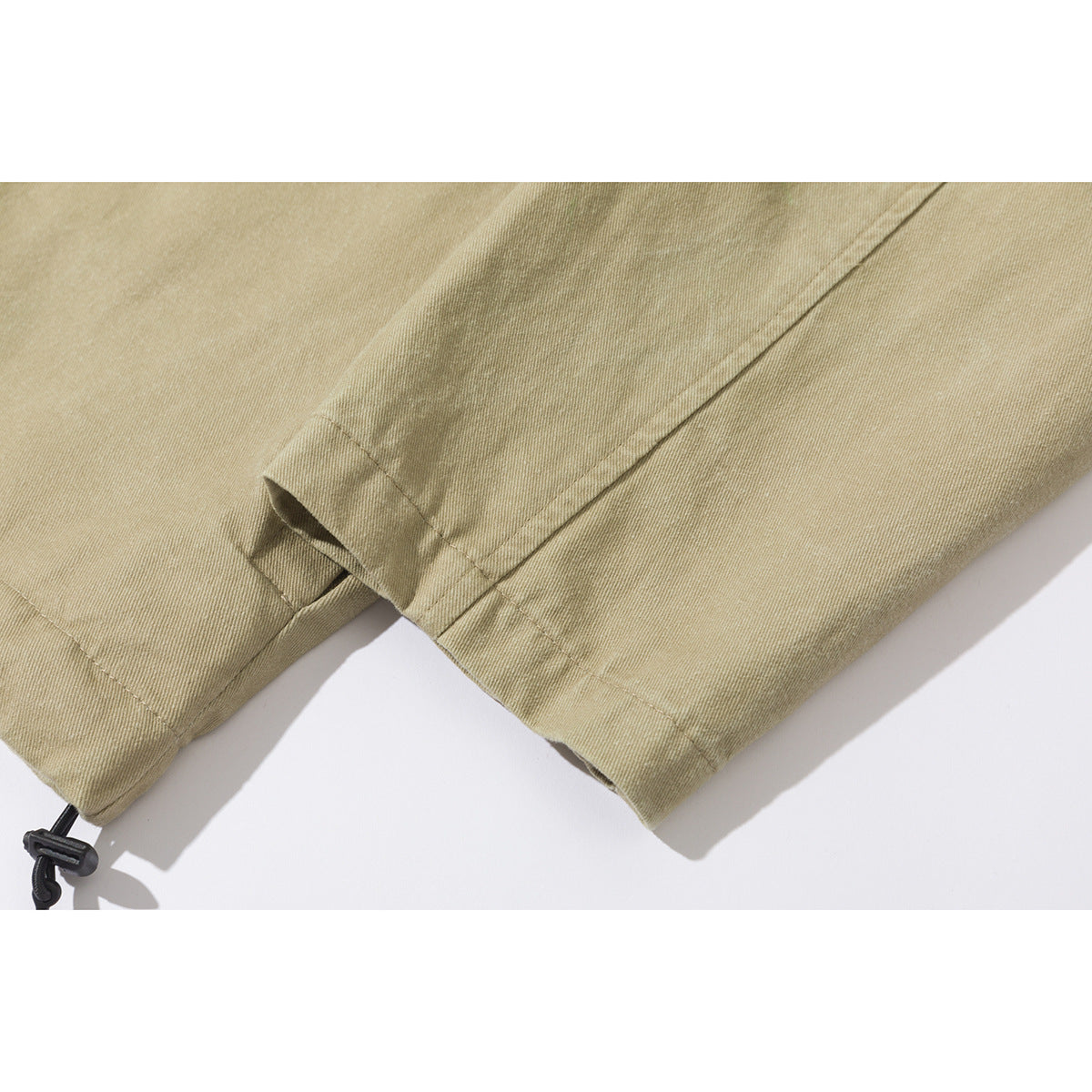 Close-up of tan jacket sleeves and cuffs, including a black drawcord toggle.