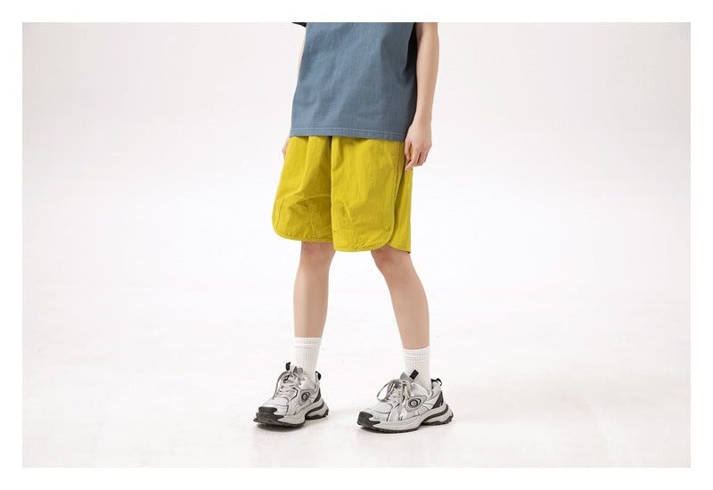Model wearing bright yellow shorts, shown from a rear three-quarter angle.