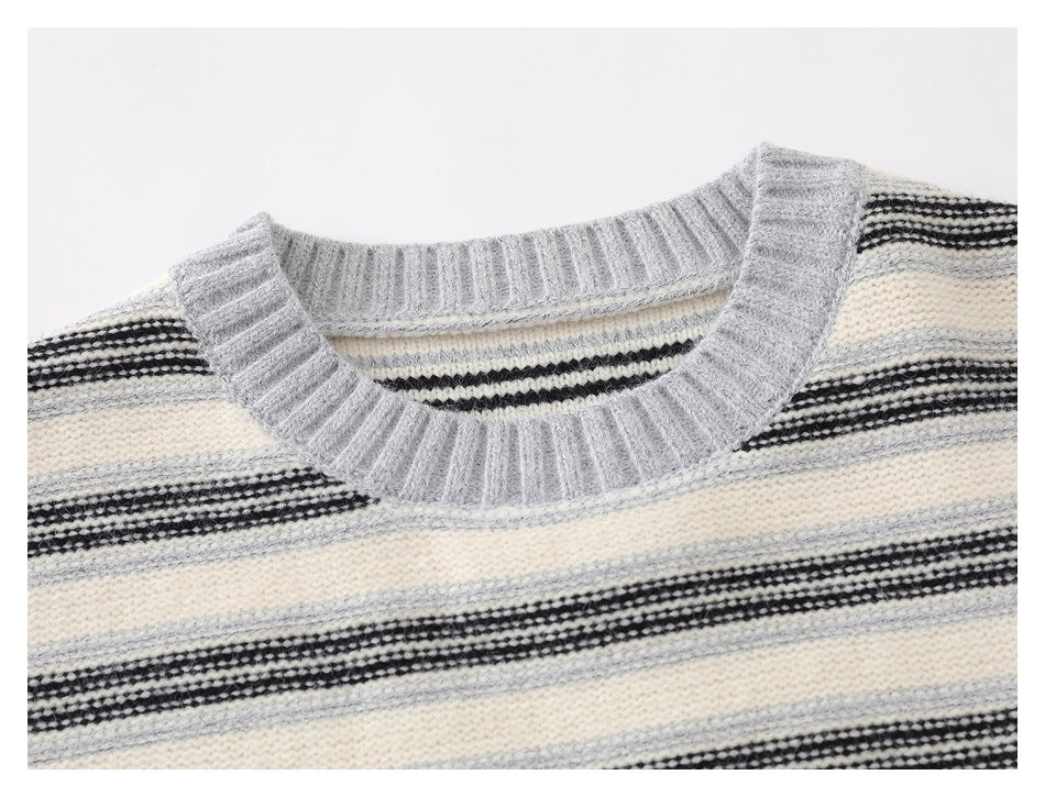 Close-up of a light gray ribbed crew neck and cream sweater with black and gray stripes.