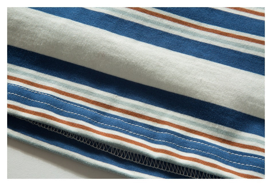 Close-up of the striped T-shirt hem showing stitched seams and the cream, blue, rust, and pale green pattern.