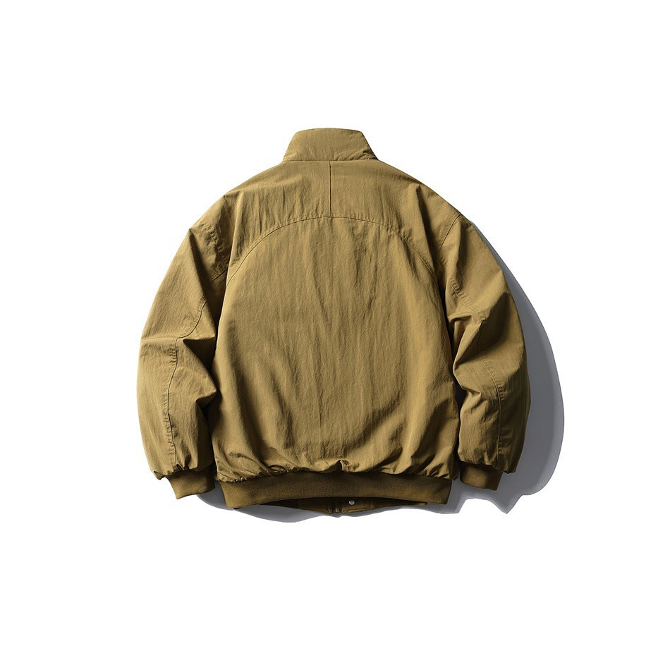 Back view of a tan jacket laid flat, showing its stand collar, curved yoke seam, and ribbed hem and cuffs.
