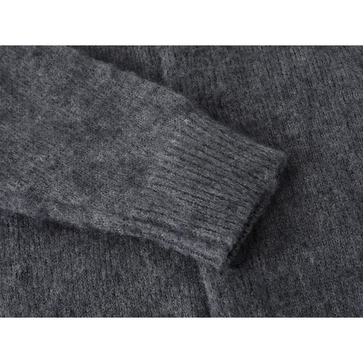 Close-up of charcoal gray knit fabric with a folded edge and partially visible button.