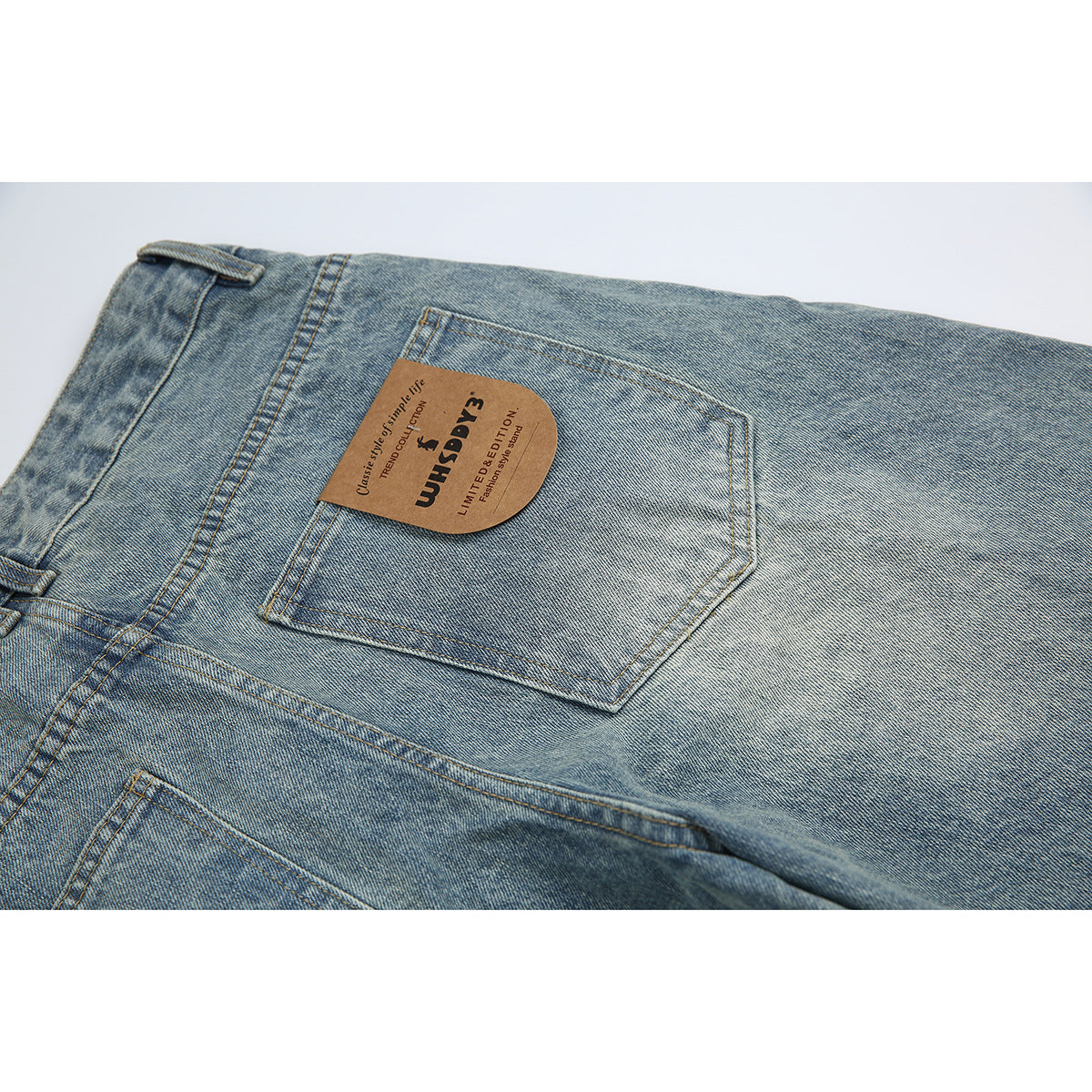 Close-up of the back of light blue washed jeans with a rear pocket and brown brand patch.