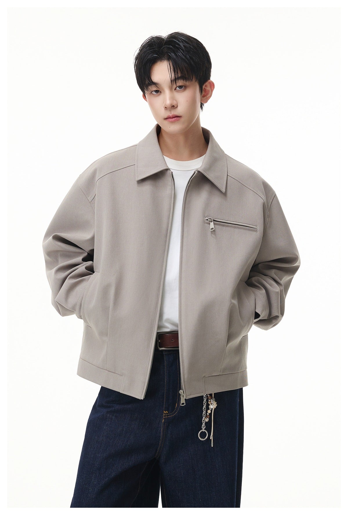 Model wearing a light taupe zip-front jacket with a pointed collar, chest zipper pocket, and side pockets.
