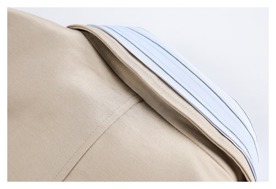 Close-up of beige garment seams edged with light blue striped fabric.