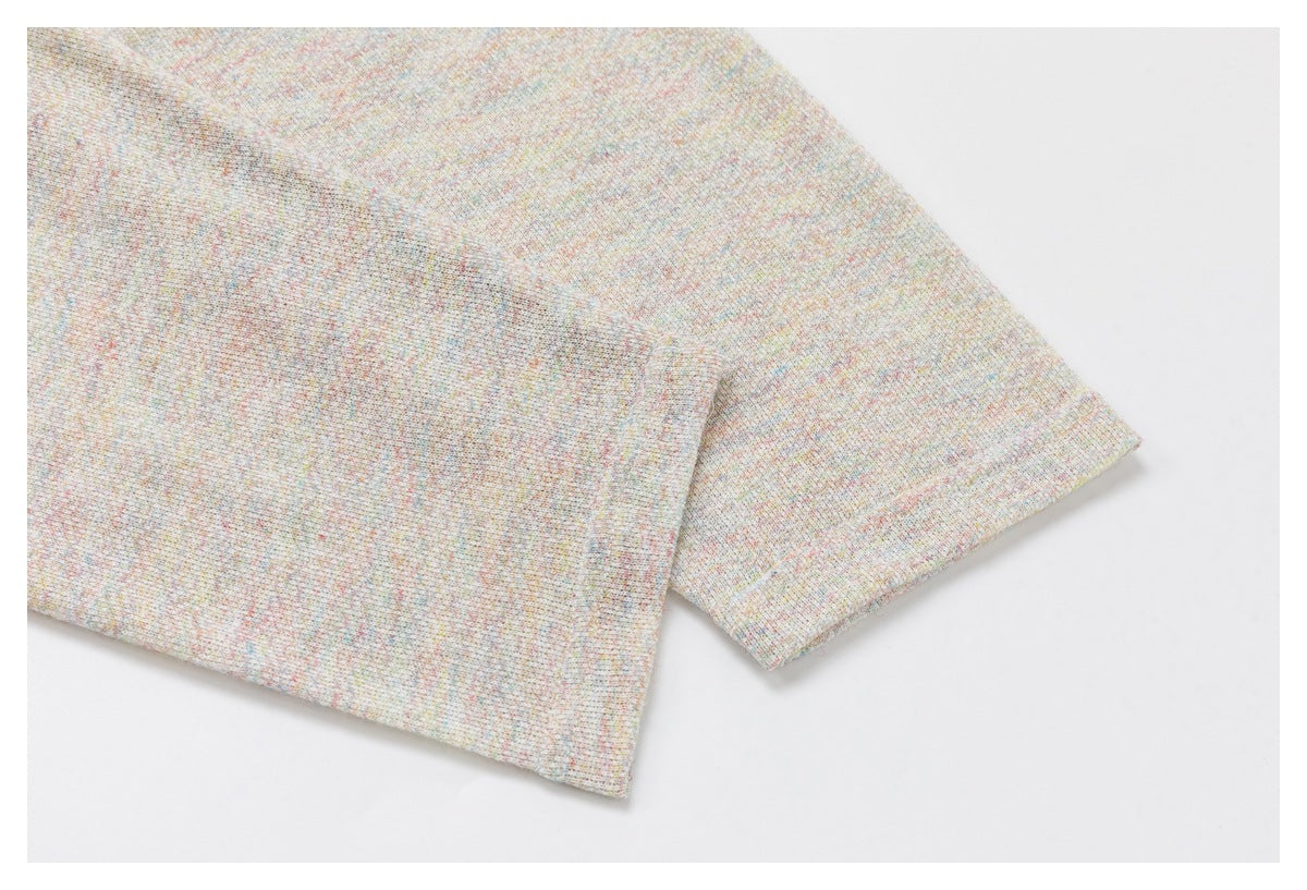 Close-up of overlapping edges of pale, finely speckled fabric.