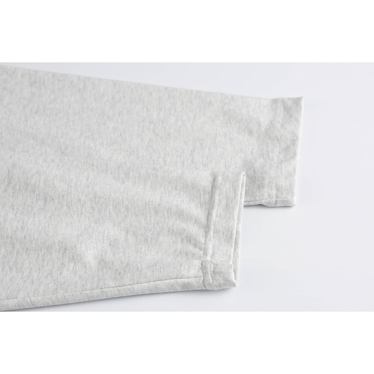 Close-up of the light gray T-shirt's sleeve, side seam, and bottom hem.