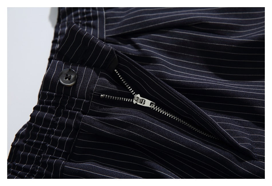 Close-up of dark pinstriped trousers with the waistband button and metal fly zipper open.