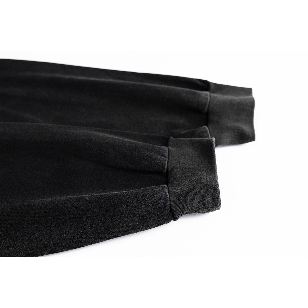 Close-up of two black T-shirt sleeves with wide ribbed cuffs.