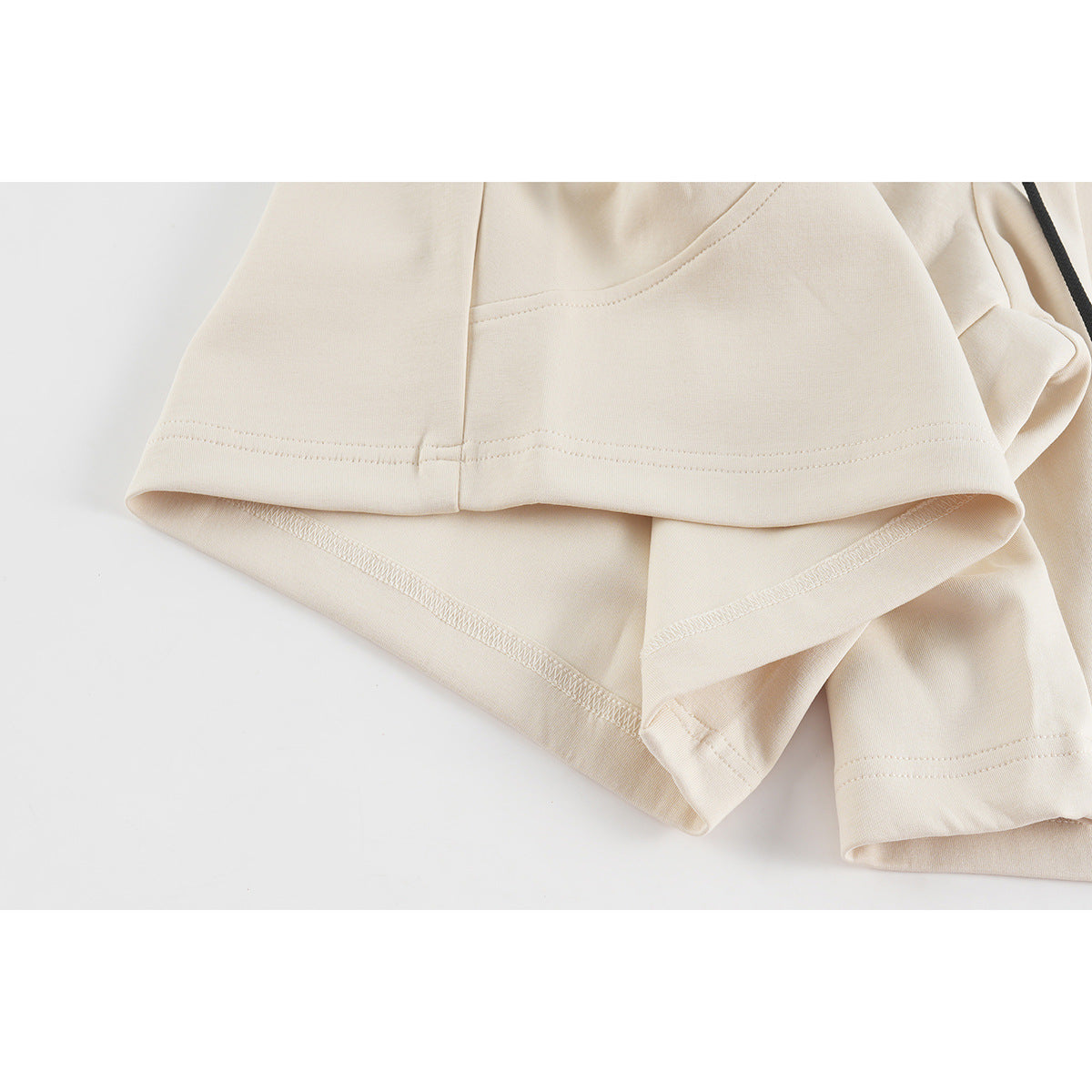 Close-up of cream shorts showing stitched hems and the inside seam finish.