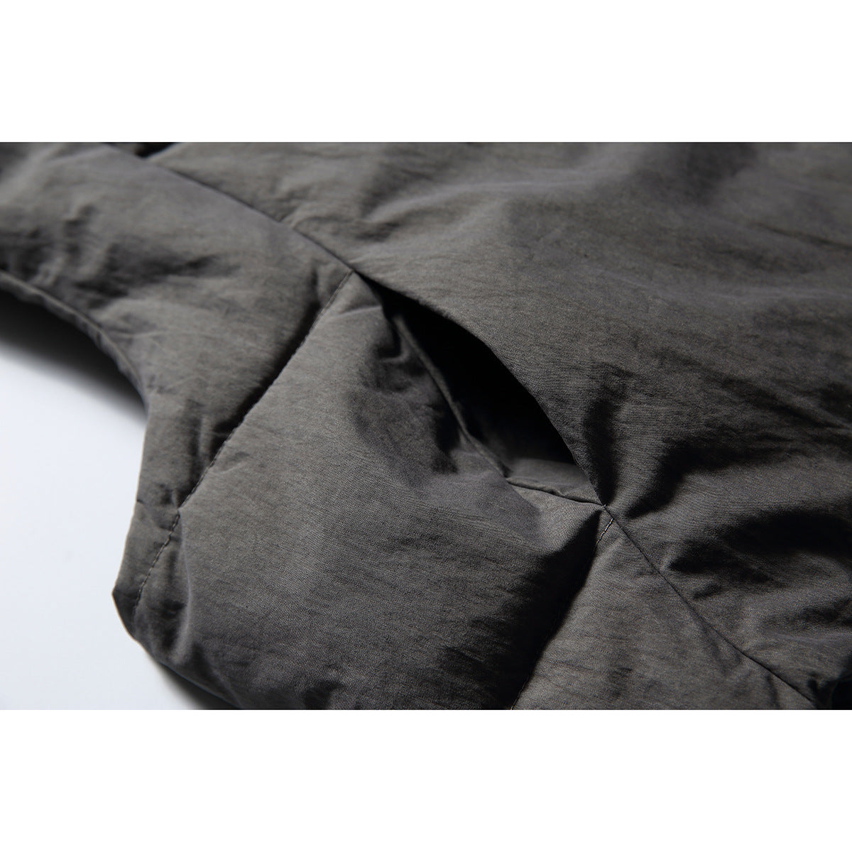 Close-up of charcoal-gray padded vest fabric and angular stitched seams.