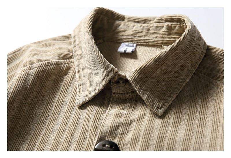 Close-up of a tan textured shirt's pointed collar, neckline label and dark front buttons.