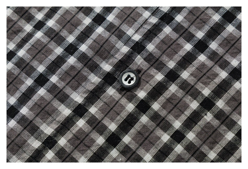 Close-up of black, gray, and white plaid shirt fabric with a dark button.