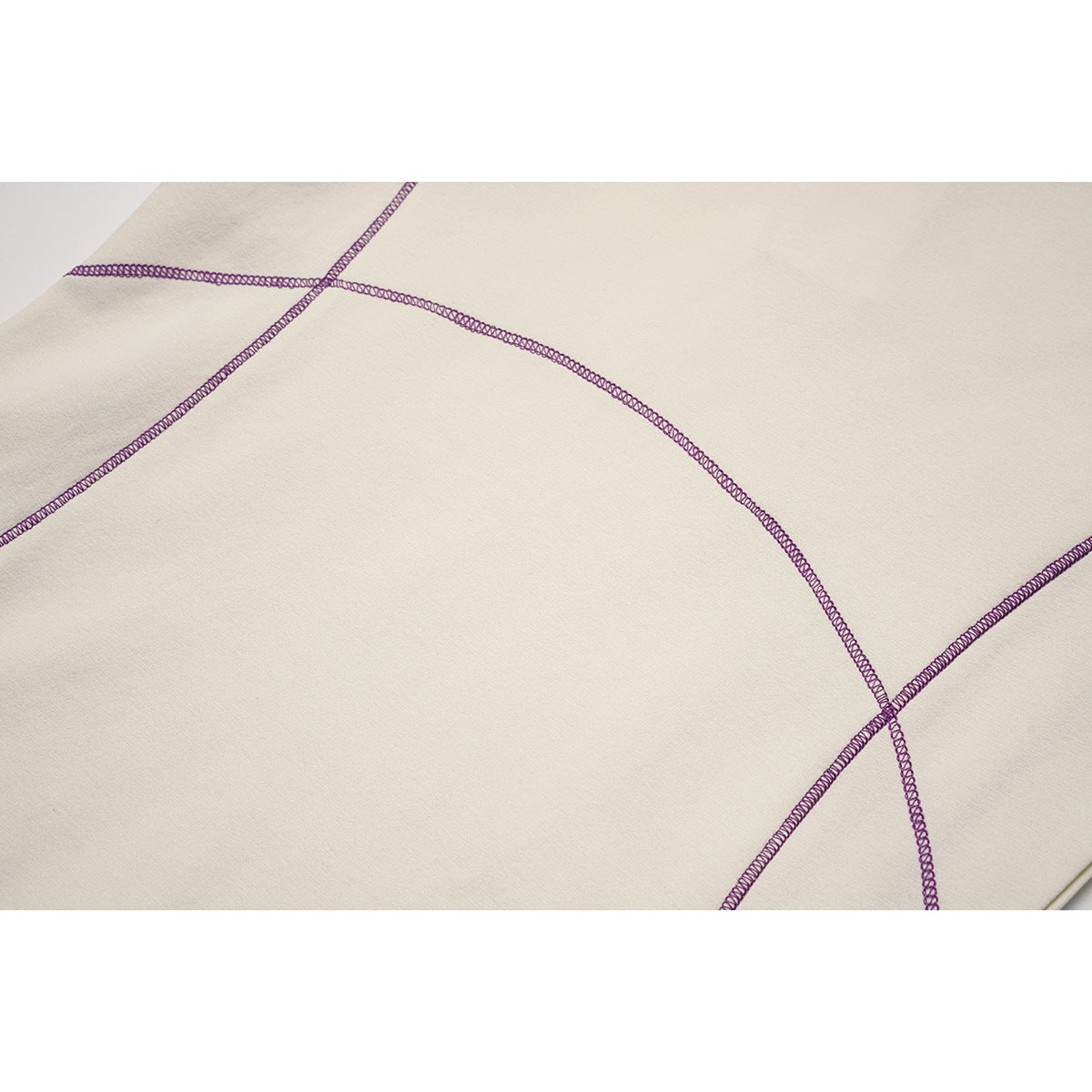 Close-up of purple overlock seams crossing the ivory fabric of a top.