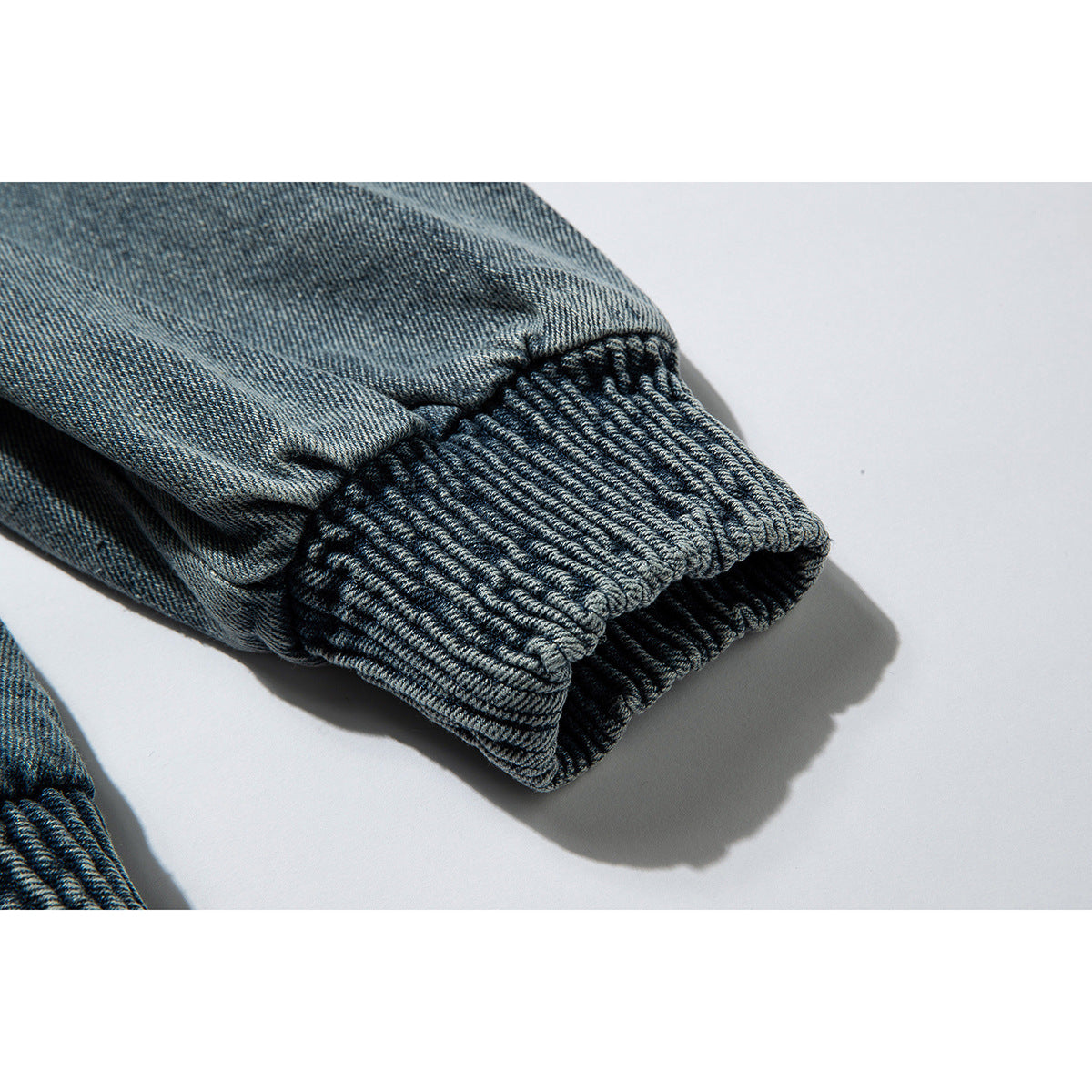 Close-up of a gathered elastic cuff on a blue denim jacket sleeve.