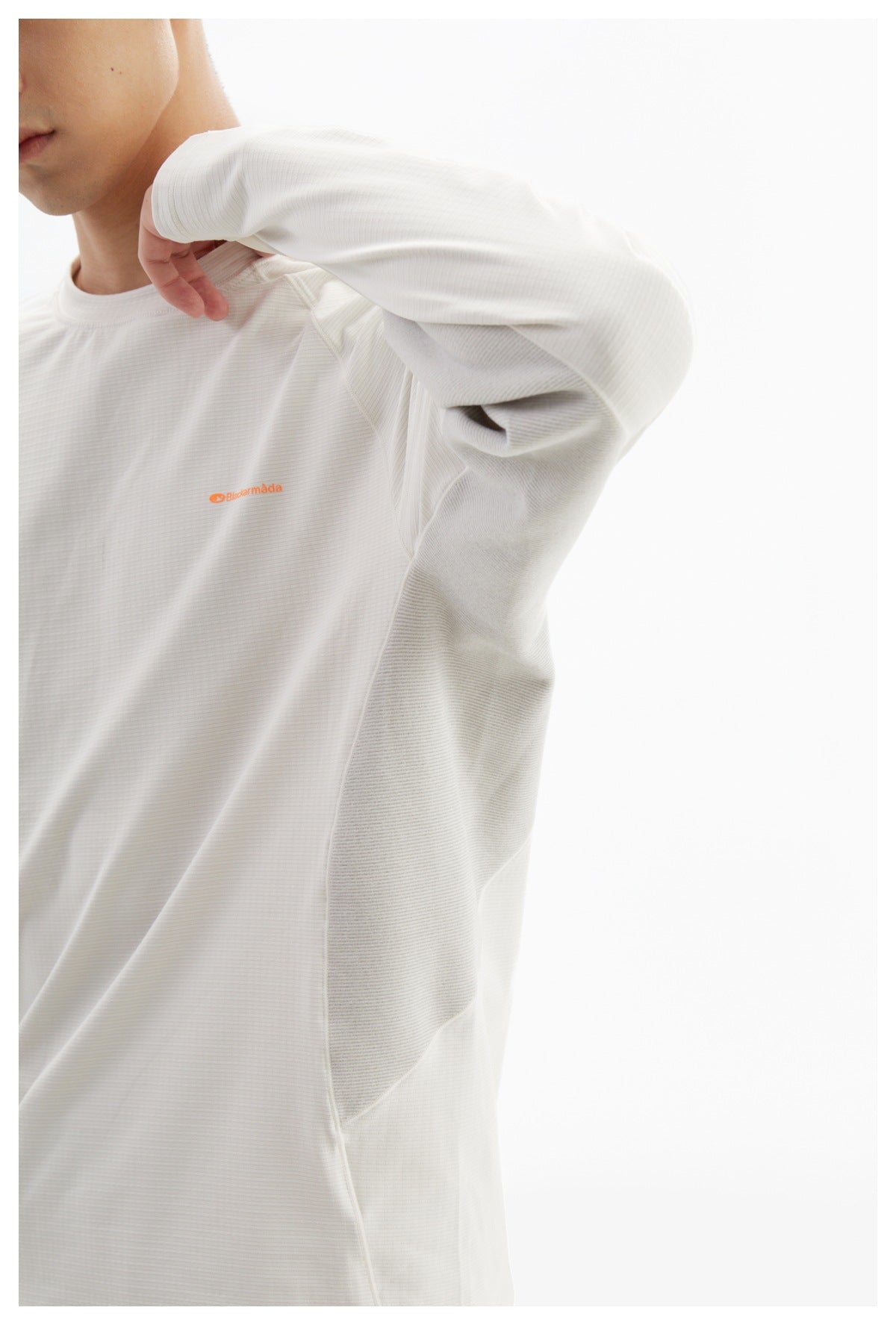 Close-up of a white long-sleeve shirt showing its fine horizontal texture, seams, and small orange chest logo.